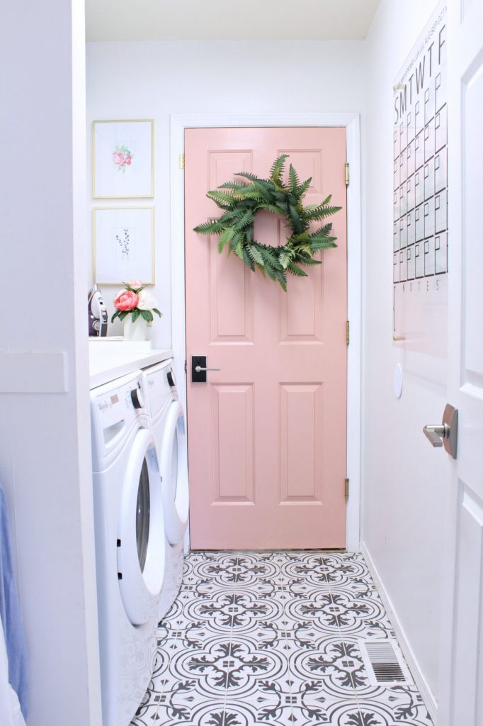 small bright laundry room with pink door