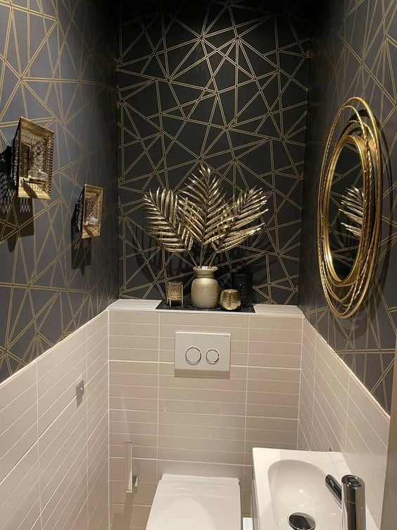 dark gray powder room with gold geometric wallpaper and accents